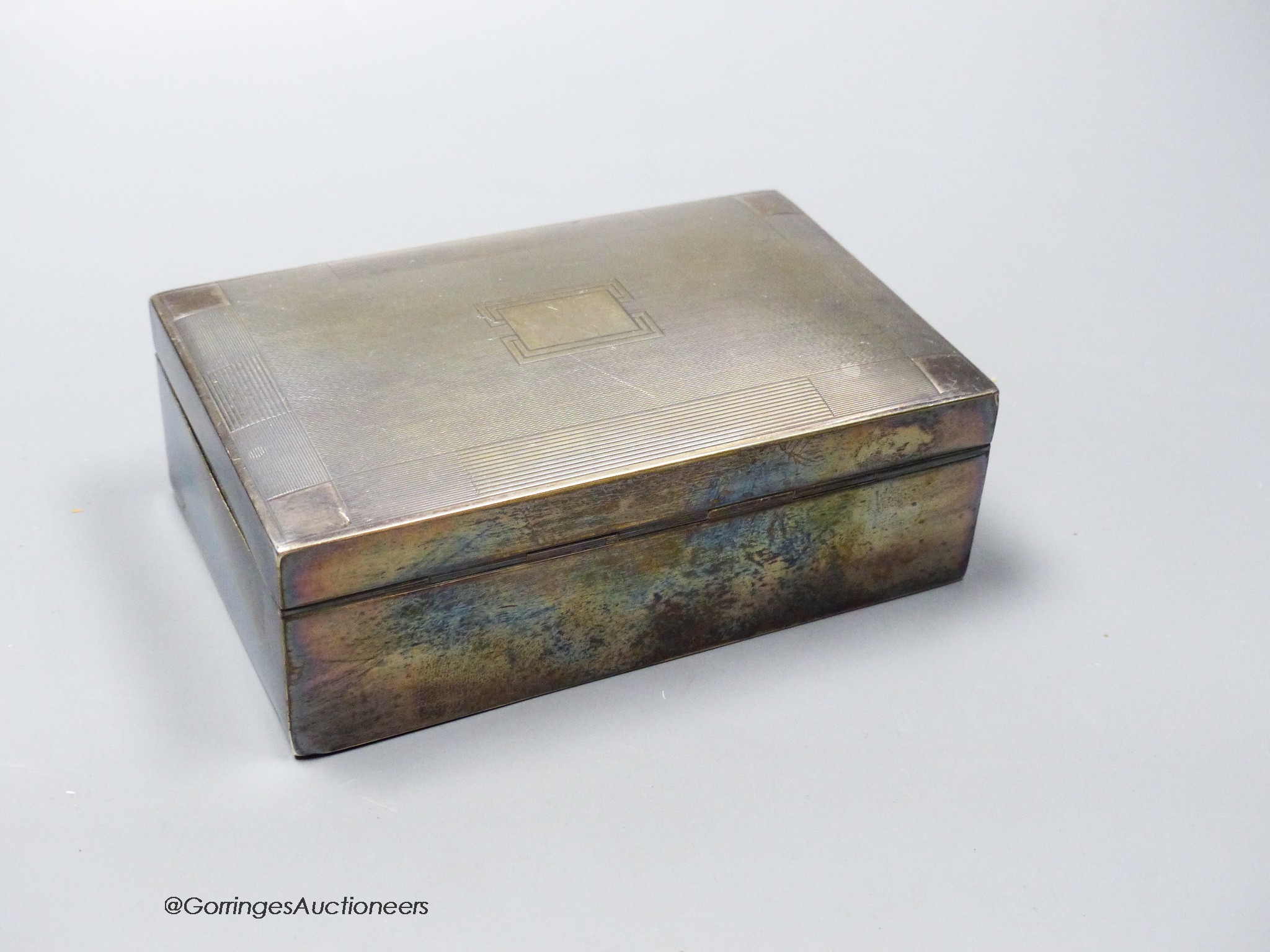 A George V silver mounted rectangular cigarette box, 13.7cm, a silver matchbox sleeve and a sterling cigar piercer.